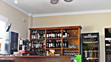 A bar area with a wooden bar counter, a wine rack, and a refrigerator.