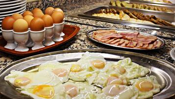 Ein Buffet mit verschiedenen Speisen, darunter Eier, Speck und weitere Frühstücksoptionen.