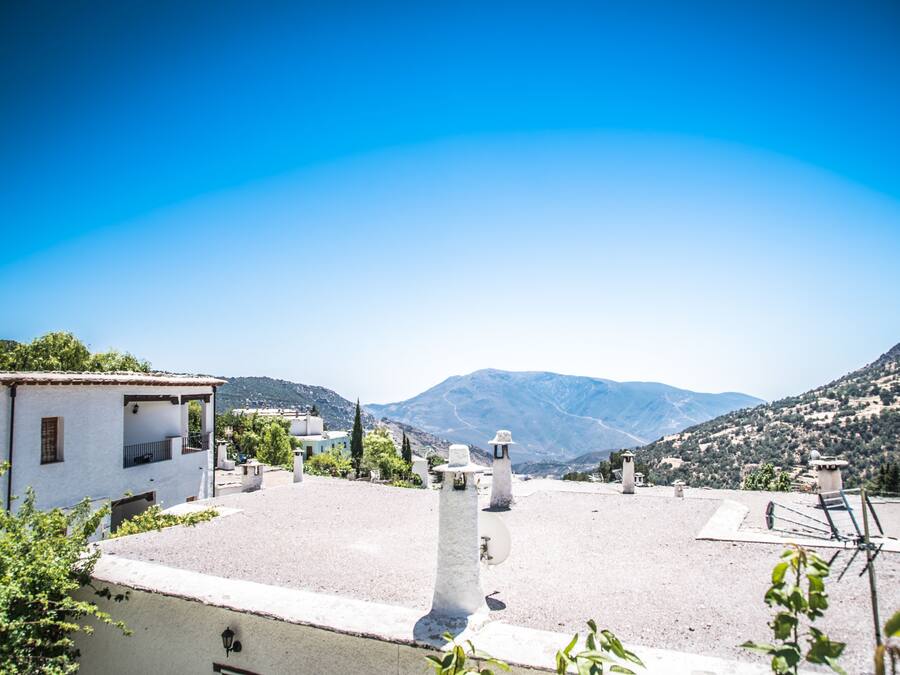 Un edificio bianco con un balcone, un muro bianco con un'antenna parabolica e un cielo azzurro limpido.