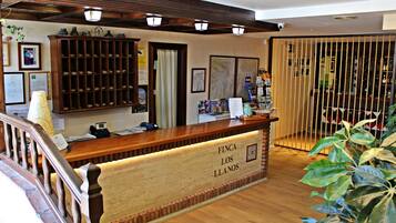 A reception desk with a wooden finish and a sign reading "FINCA LOS LLANOS".