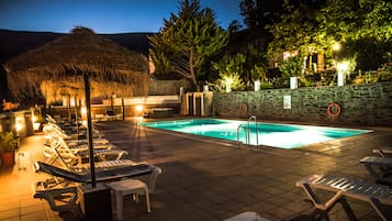 Una piscina al aire libre de temporada, sombrillas