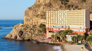 A hotel with multiple floors, located near a rocky coastline and beach. - Mirador del Cabo Hotel Adults Recommended (Enix)