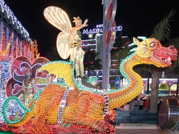 Una exhibición decorativa e iluminada con una serpiente grande y un adorno en la parte superior, frente a un cartel de hotel.