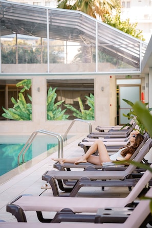 Una piscina cubierta, una piscina al aire libre, tumbonas