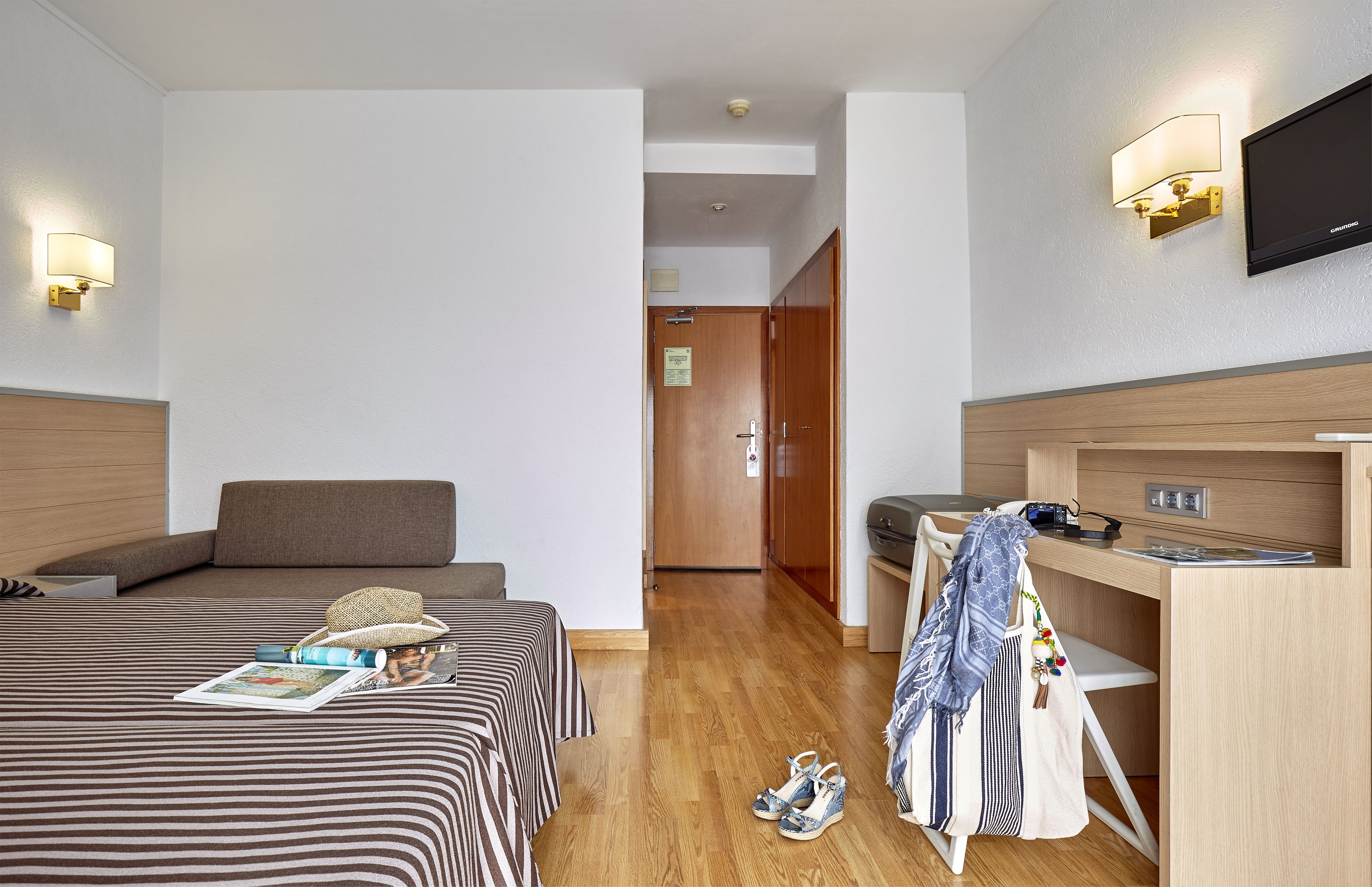Ein Hotelzimmer mit zwei Betten, einem Schreibtisch, einem Stuhl und einem Fernseher.