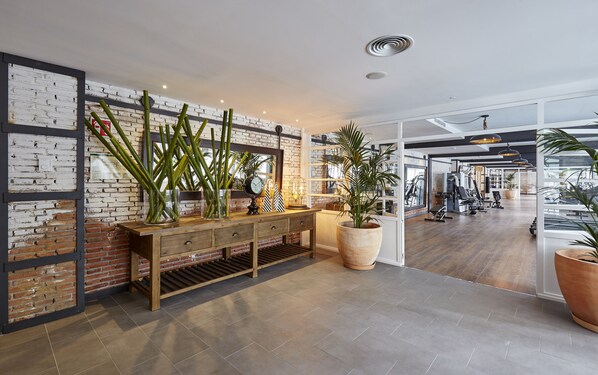 A gym with wooden flooring, a brick wall, and various exercise equipment.