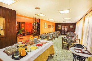 Ruokailutila, jossa on aamiaista varten katetut pöydät, monipuolinen buffet ja suuri ikkuna, jossa on verhot.