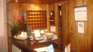 Un taulell de recepció de fusta amb un ordinador, un telèfon i diversos documents.