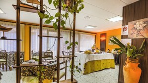 Un espace repas avec des tables, des chaises et une grande plante en pot.