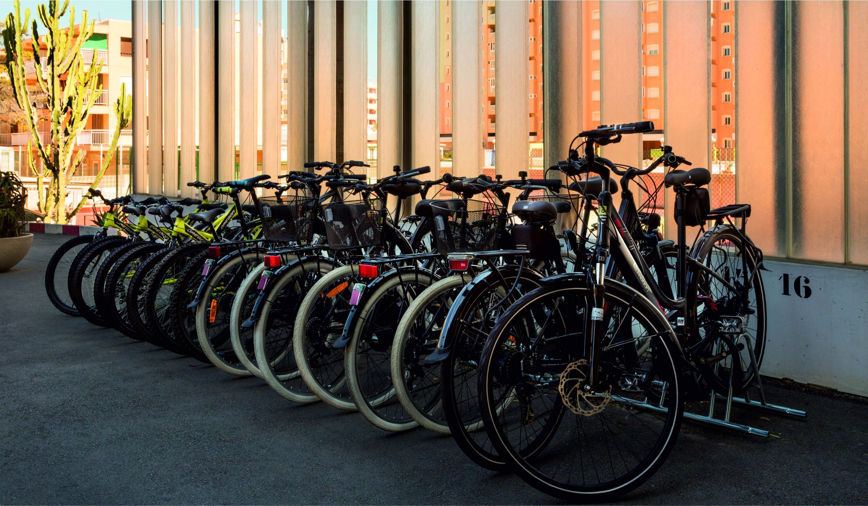A row of bicycles parked against a building with a number 16 on the wall.