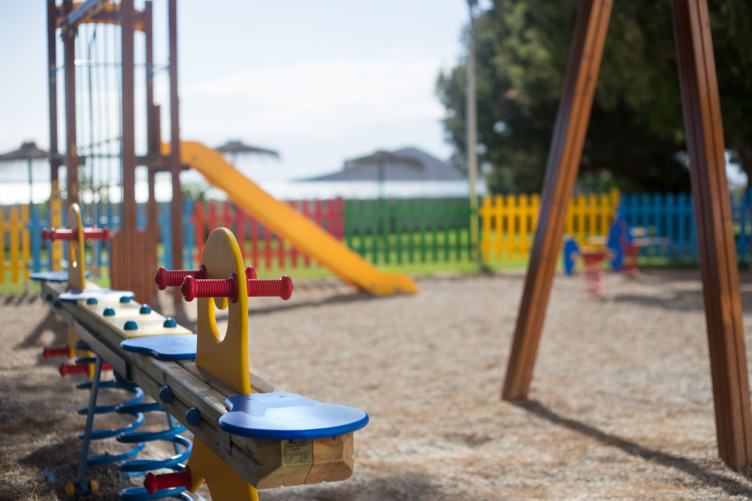 Un parque infantil con varios juegos, incluyendo un balancín y un tobogán.