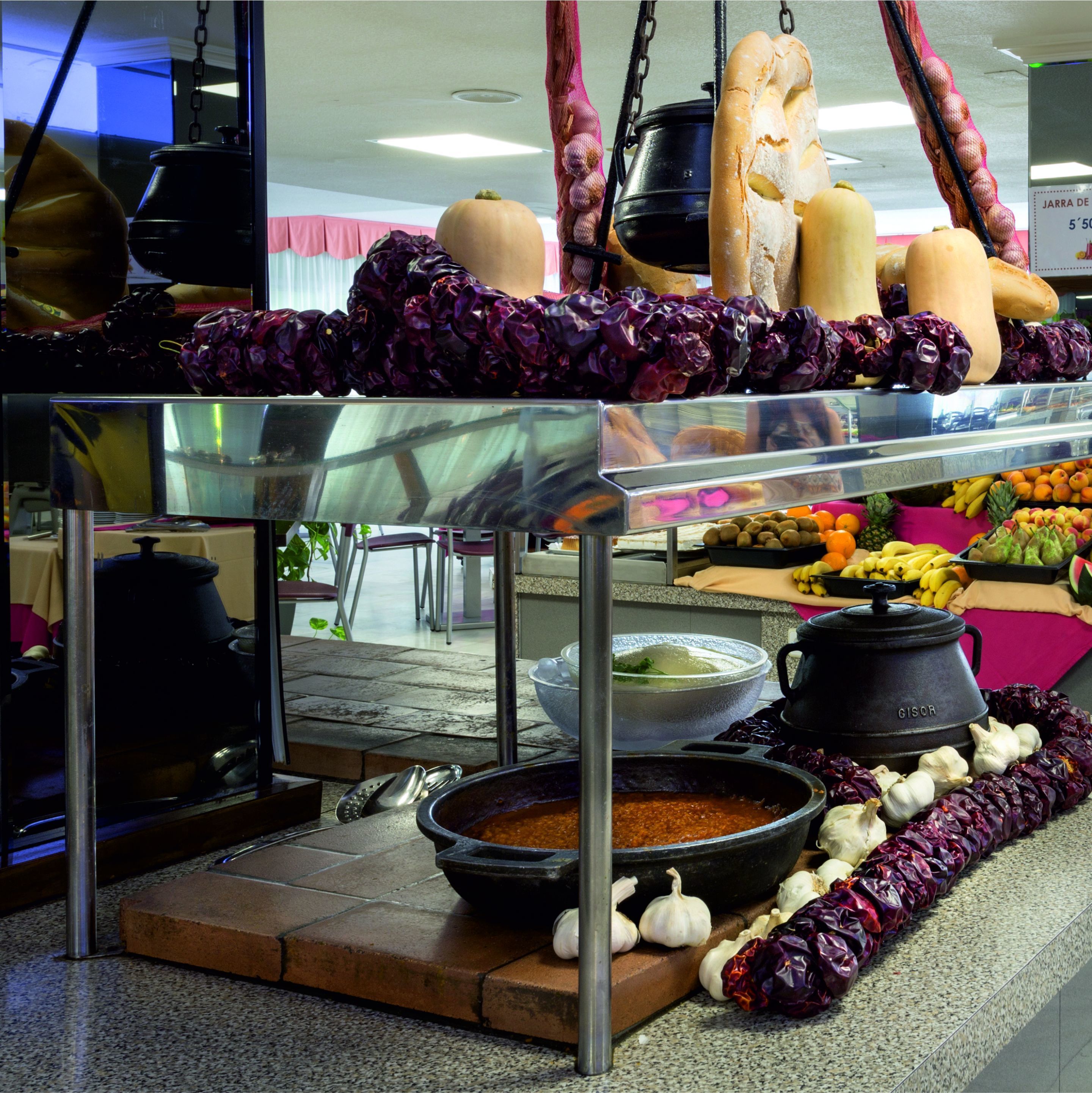 A kitchen counter with various cooking utensils, pots, and vegetables.