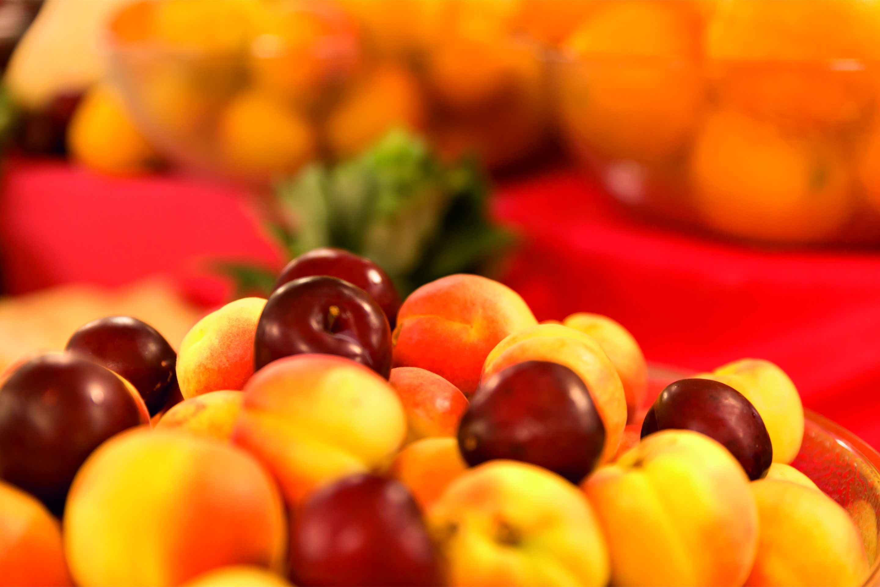 Primer plano de un frutero lleno de melocotones y ciruelas.