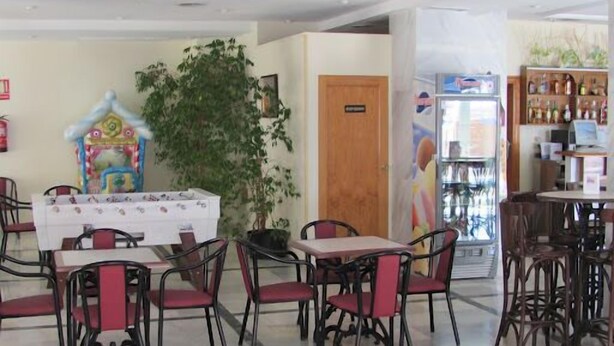 A restaurant with tables and chairs, a refrigerator, and a display of bottles. - La Mirage (Cartagena)