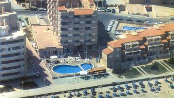 Een buitenzwembad, ligstoelen bij het zwembad