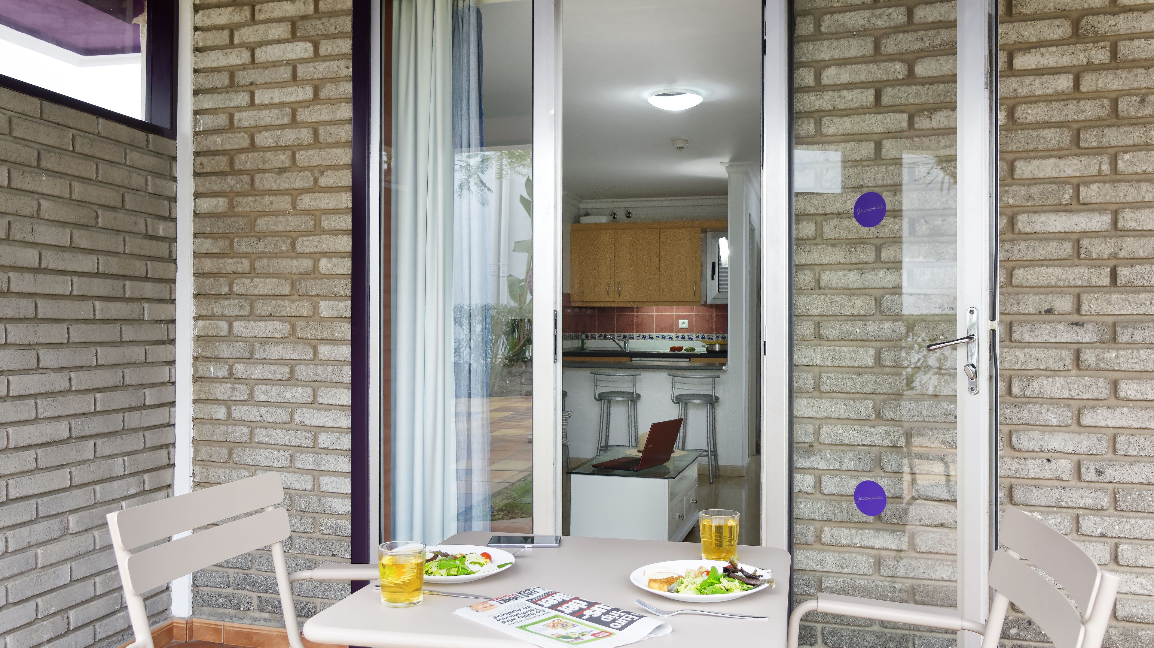 A dining area with a table set for two, a glass of beer, and a menu.
