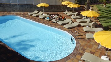 A swimming pool with lounge chairs and yellow umbrellas.