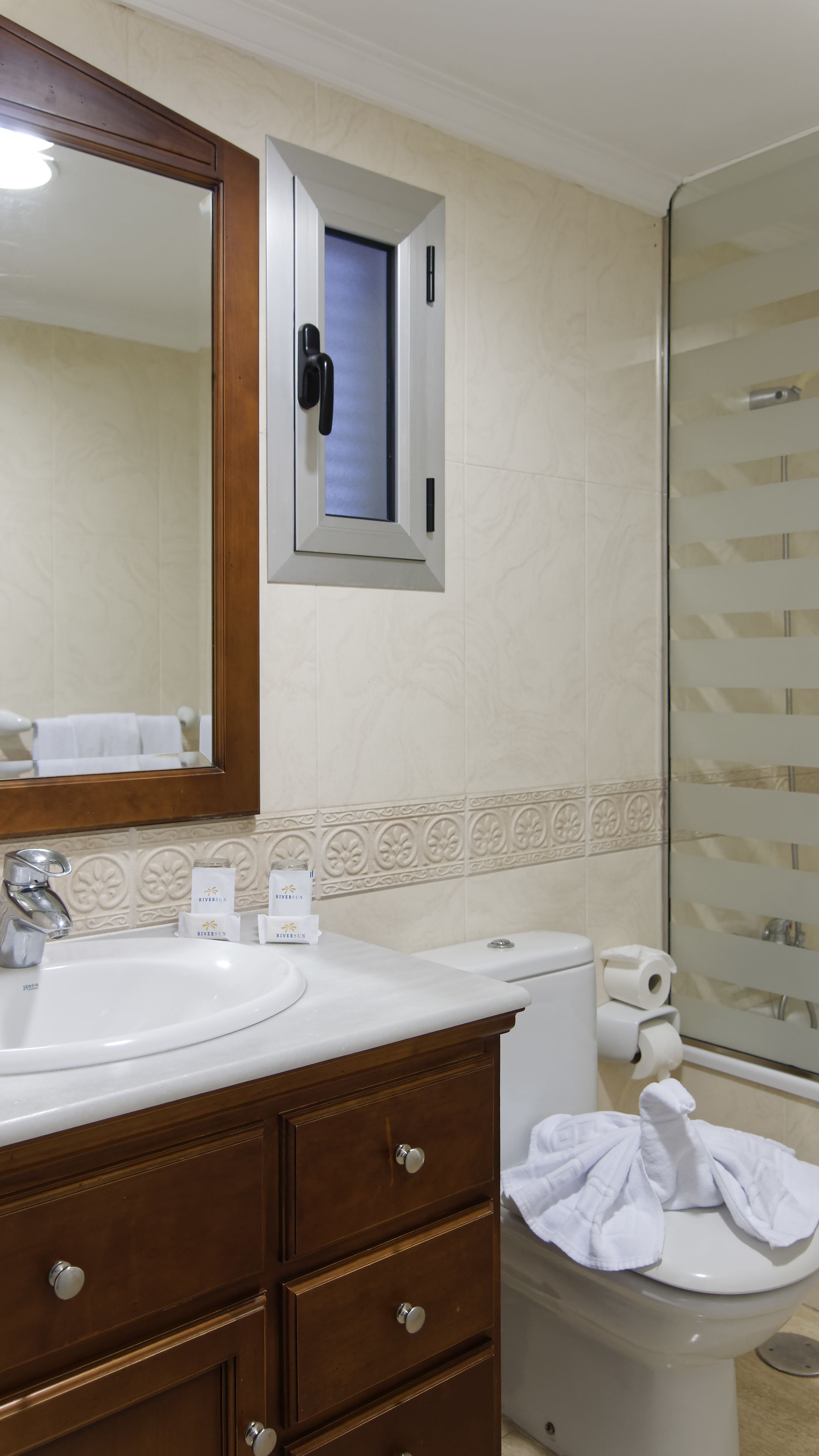 Un baño con lavabo blanco, espejo, inodoro y zona de ducha.