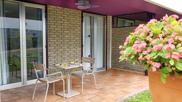 A patio with a table and chairs, a potted plant, and a brick wall.