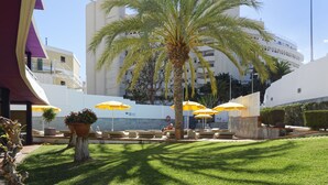 A courtyard with palm trees, outdoor seating, and umbrellas. - Jacarandas Beach (San Bartolomé de Tirajana)