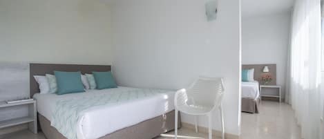Ein modernes Schlafzimmer mit einem Bett, einem weißen Stuhl, einem Nachttisch und einem kleinen Tisch mit einer Lampe und Blumen.
