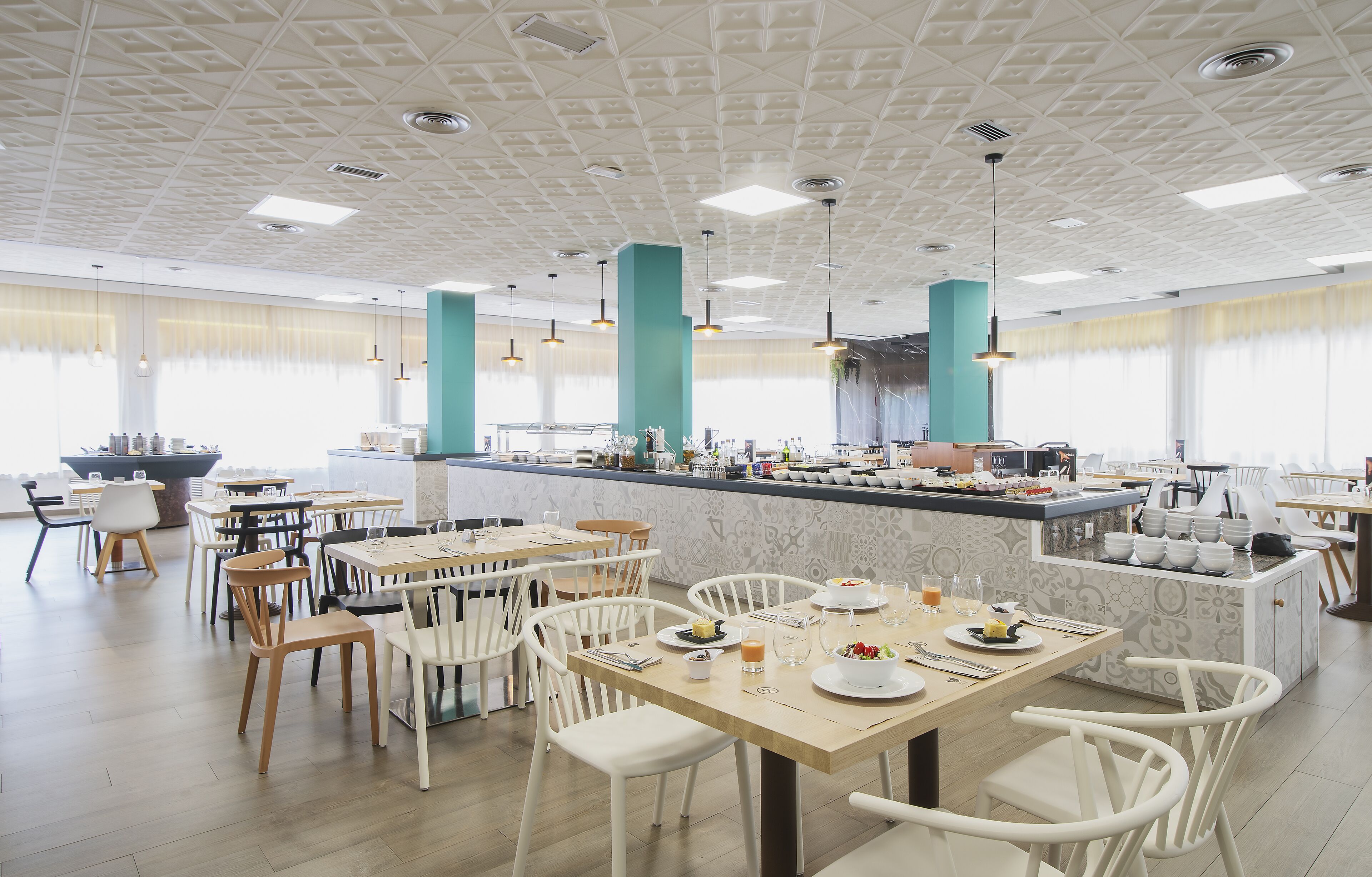 A modern dining area with white chairs, tables, and a central bar area with a marble countertop.