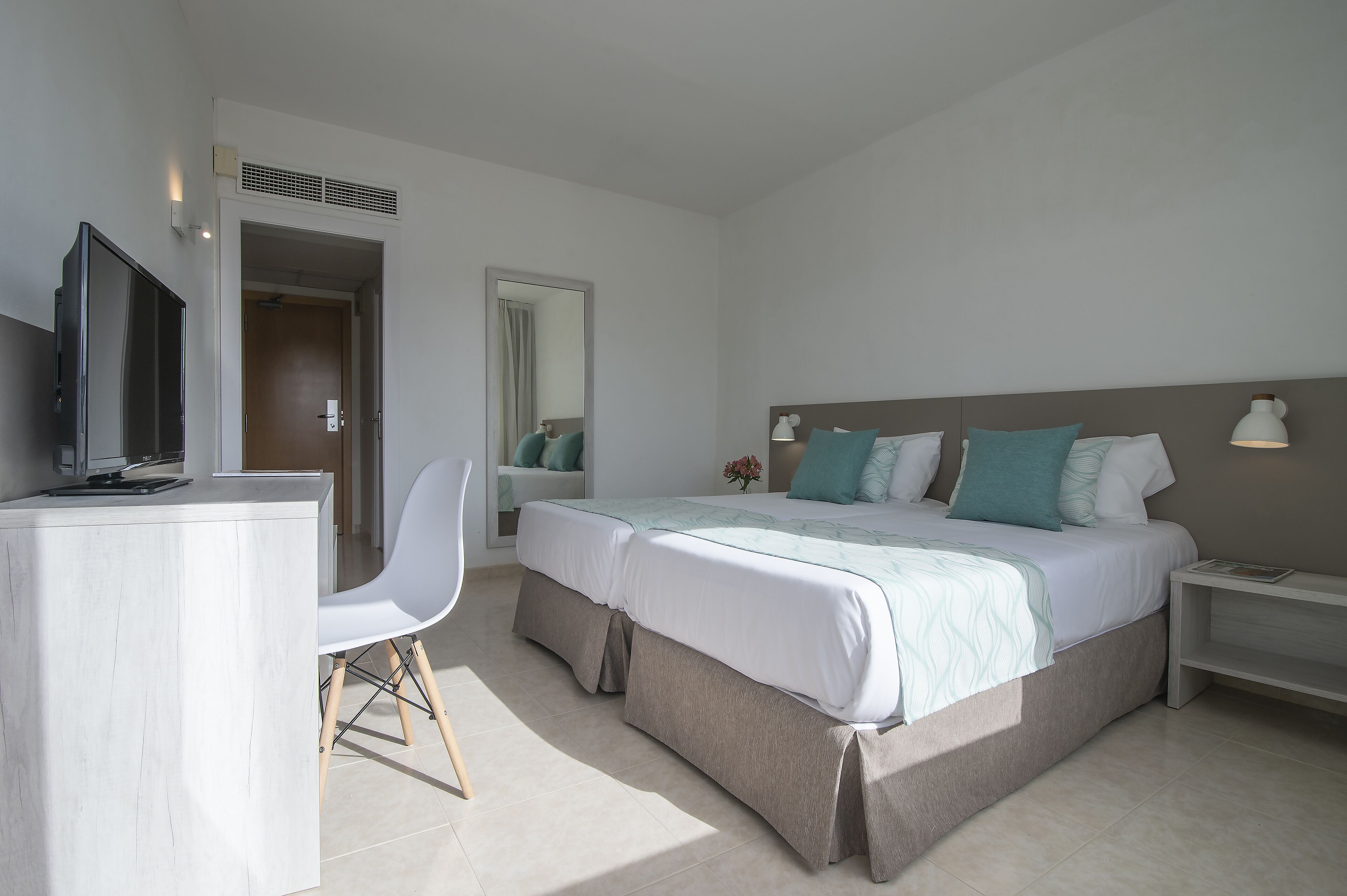 Una habitación de hotel moderna con una cama, mesitas de noche, un escritorio y una silla.