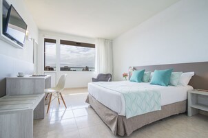 A modern hotel room with a large bed, a desk, and a chair.