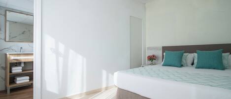 A bedroom with a bed, a nightstand, a mirror, and a wooden shelf with towels.