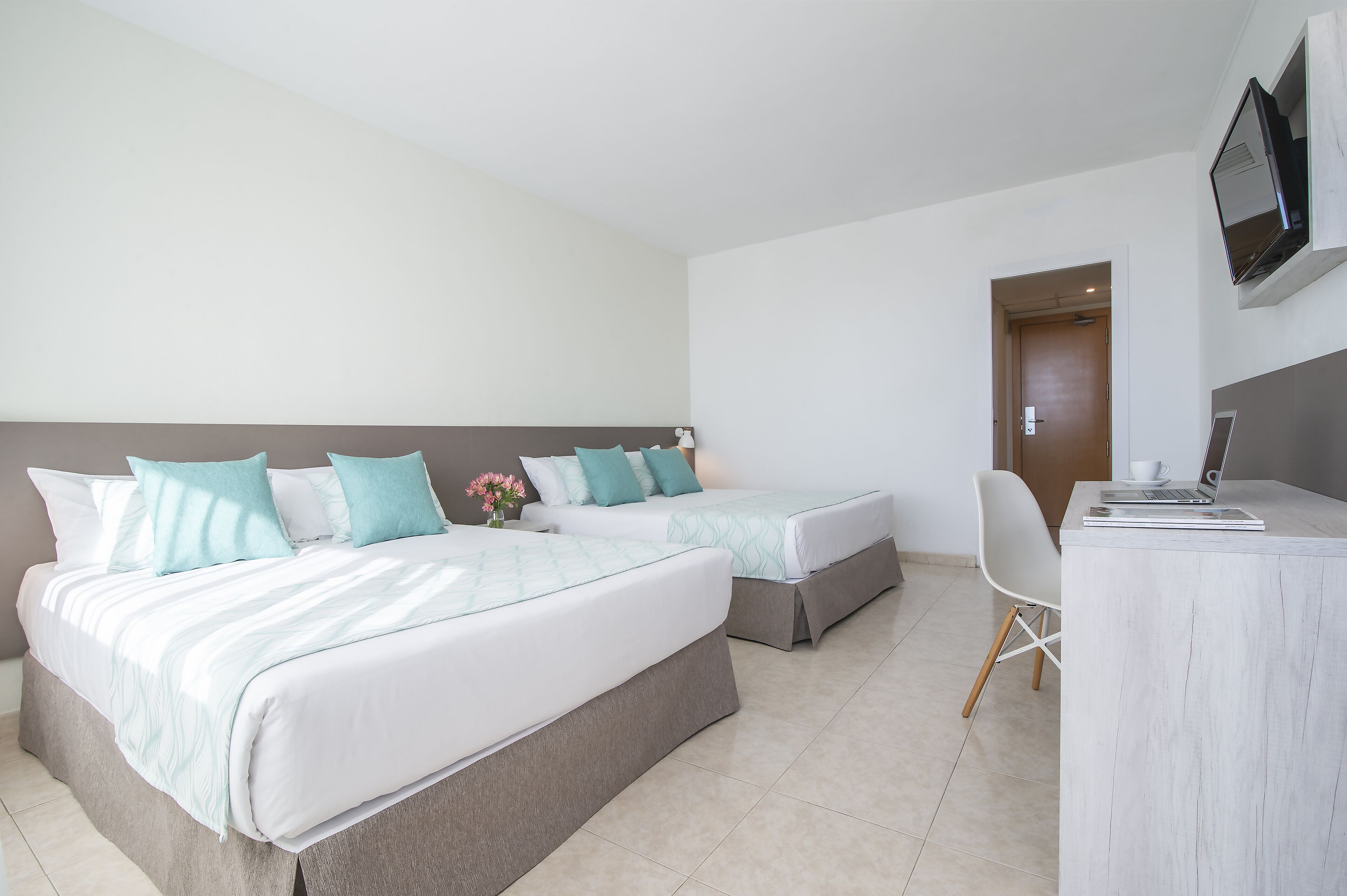 Habitación de hotel con dos camas, un escritorio y una televisión.