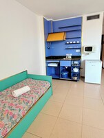 Habitación pequeña con cama, kitchenette y microondas.
