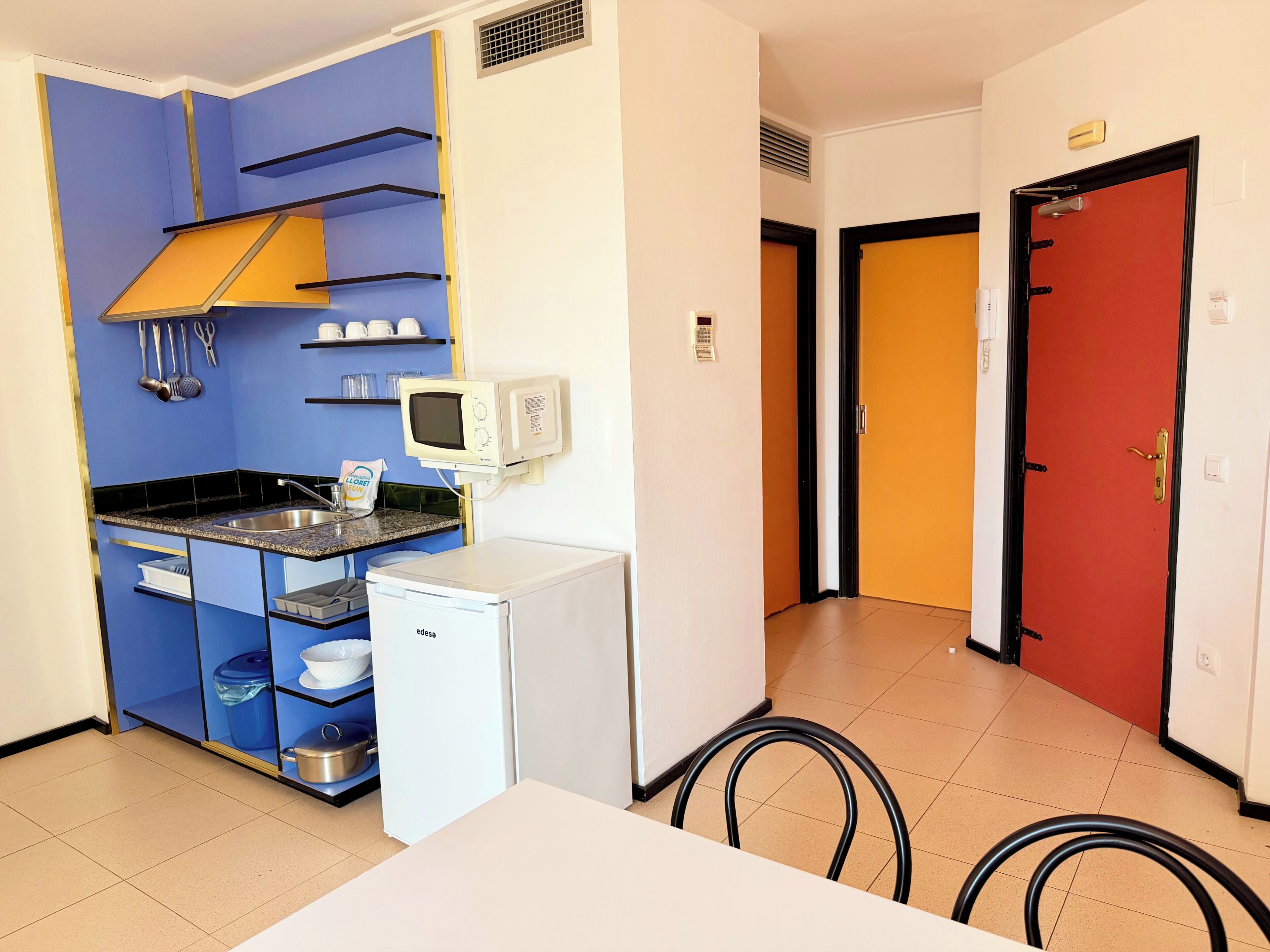 A compact kitchen with a microwave, sink, and storage shelves.