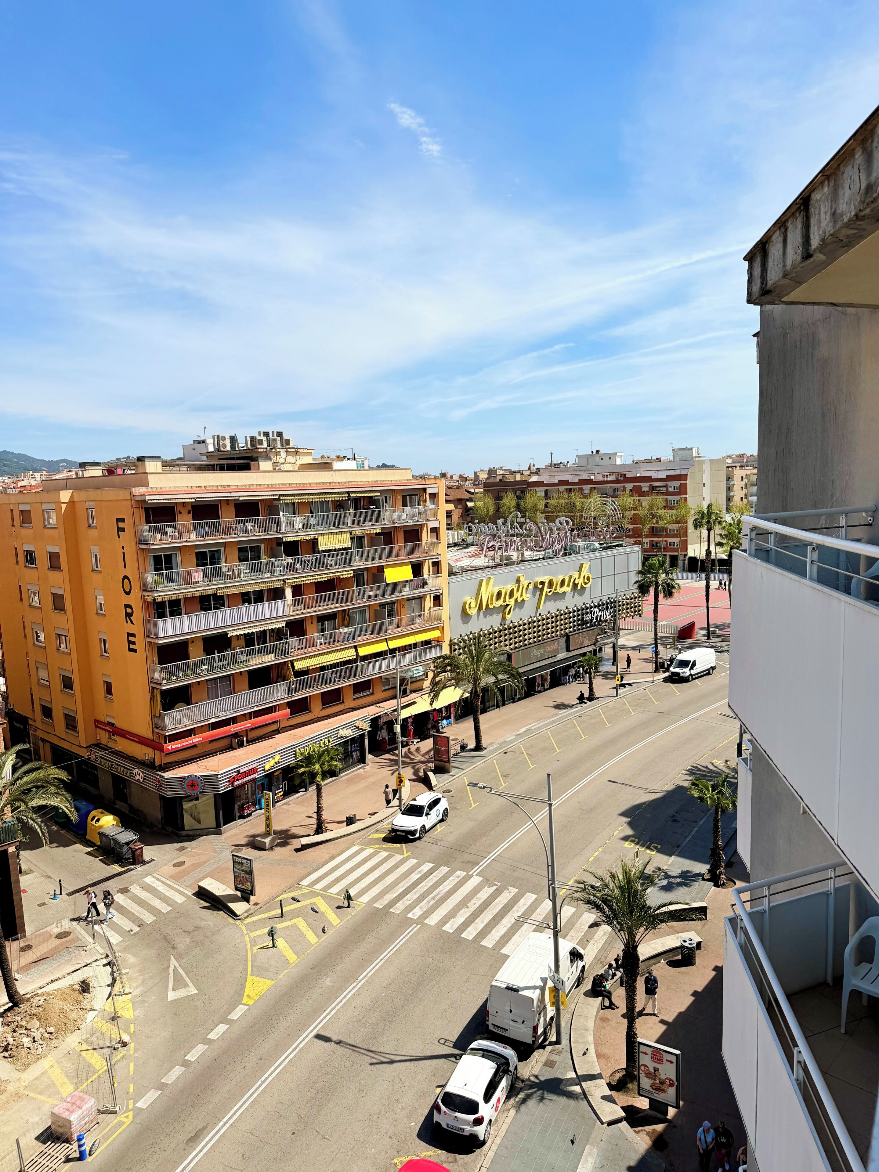 A multi-story hotel with balconies, a visible restaurant, and a street view with vehicles and pedestrians.