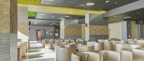 A modern hotel lobby with leather seating, a marble floor, and a green wall.