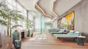 A spa area with wooden flooring, green lounge chairs, and large vases.