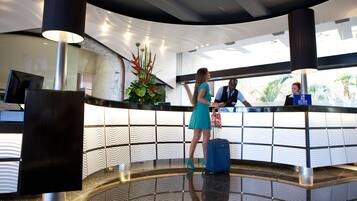 A reception area with a modern design, including a reception desk, a large decorative plant, and a curved ceiling with recessed lighting.