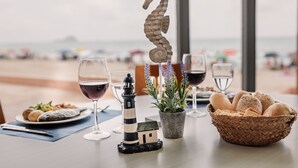 A table with a basket of bread, a potted plant, a lighthouse decoration, and a glass of wine. - Aparthotel Londres (San Javier)