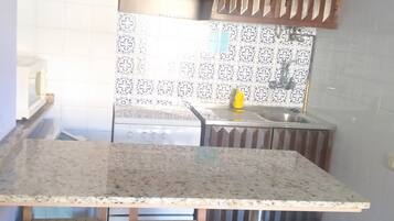 Una cocina con encimera de granito, sillas de madera y baldosas estampadas.