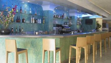 A bar area with a marble countertop, multiple shelves of bottles, and wooden bar stools.