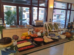 A buffet counter with various food items, including fruits, meats, and cheeses. - Aparthotel Londres (San Javier)