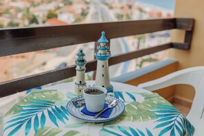 A table with a cup of coffee, a plate, and a spoon on a tablecloth with a leaf pattern. - Aparthotel Londres (San Javier)