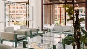 A modern hotel lobby with glass partitions, comfortable seating, and a view of the surrounding buildings. - Aparthotel Londres (San Javier)