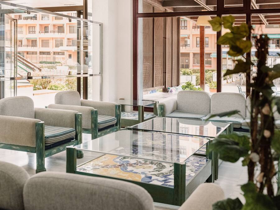 Eine moderne Hotelhalle mit Glastrennwänden, bequemen Sitzgelegenheiten und Blick auf die umliegenden Gebäude.