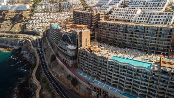 Un hôtel de grande hauteur doté de nombreux balcons, d’une piscine et offrant une vue sur la côte.