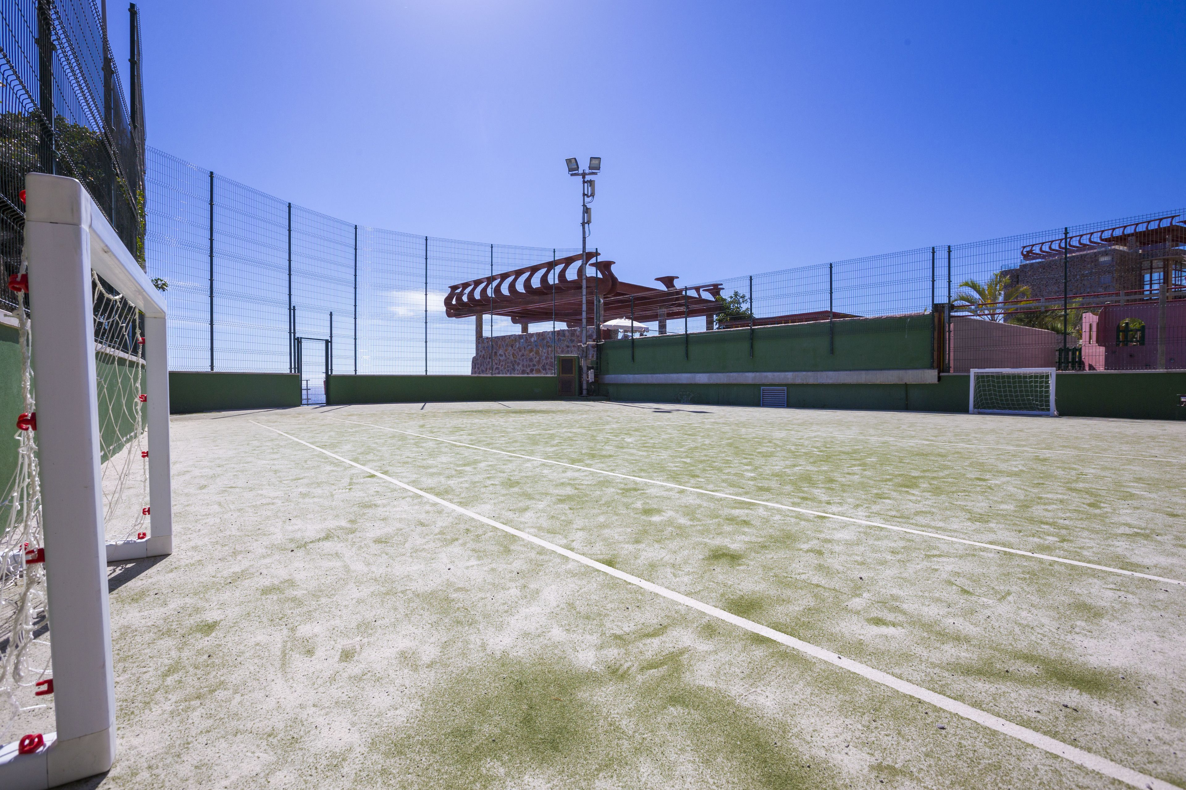 An indoor tennis court with a net, fencing, and a goal post.