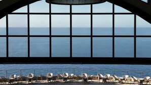 Vista desde una habitación con techos altos y ventanas amplias con vista al mar.