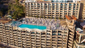 Un hôtel de grande hauteur doté de nombreux balcons, d’une piscine centrale et d’espaces de détente en plein air.