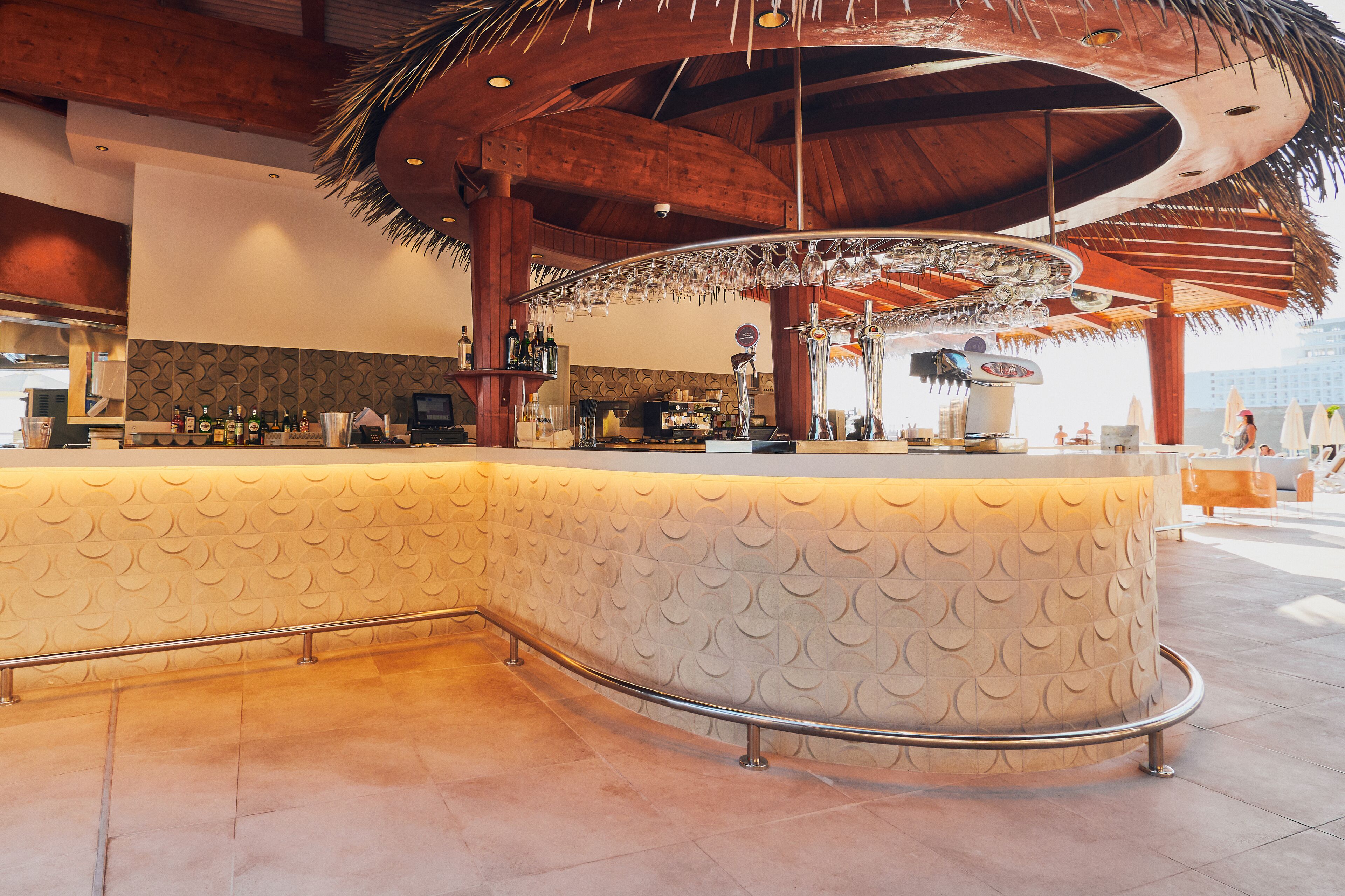 A bar area with a curved counter, a thatched roof, and a patterned wall.