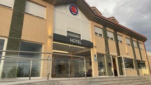 A hotel with a modern facade, a prominent 'HOTEL' sign, and a 'CAFE' and 'RESTAURANTE' sign indicating on-site dining options. - Hotel Arias Aeropuerto (Castrillon)