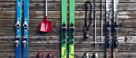 Une surface en bois sur laquelle sont disposés en rangée des skis, des bâtons de ski et des chaussures de ski.
